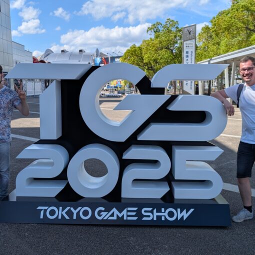 zwei Männer neben TGS 2025 Skulptur.