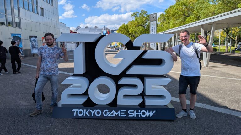 zwei Männer neben TGS 2025 Skulptur.